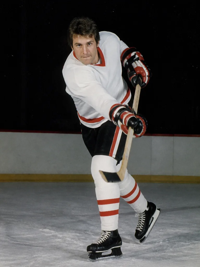 Ishockeyspelare i retrostil i vit tröja som laddar för ett slagskott