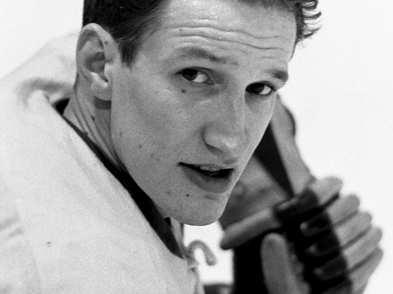 Svartvitt porträtt av Lennart Svedberg med hockeyklubban över axeln